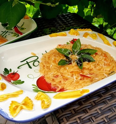 Orzo pasta with tomato sauce and fresh basil served on a decorative Italian ceramic platter.
