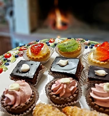 An assortment of gourmet Italian pastries and mini tarts arranged on a decorative plate by a fireplace.