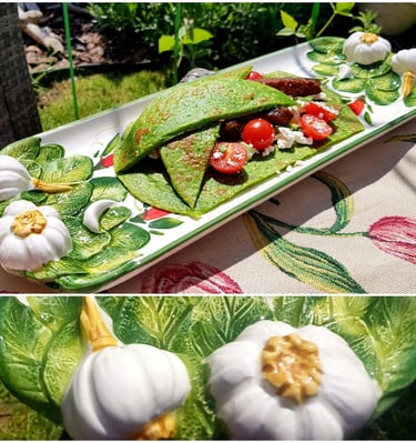 Savory green spinach crepes filled with steak, cherry tomatoes, and feta on a garlic-themed ceramic platter.