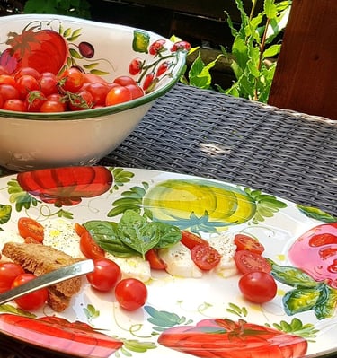 Fresh Caprese salad with cherry tomatoes and mozzarella on a decorative plate outdoors.