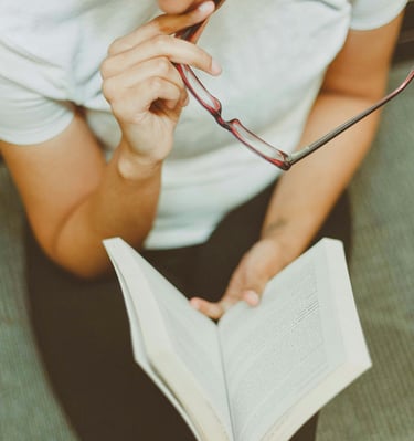 a man in glasses and a white shirt is holding a book