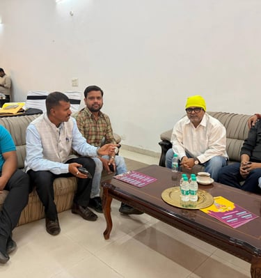 A group of men having a formal discussion while sitting on sofas around a wooden coffee table.