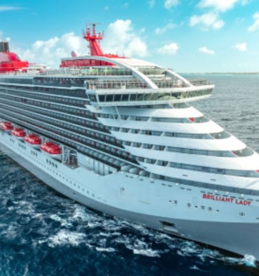 The Virgin Voyages Brilliant Lady cruise ship sailing on the blue ocean under a sunny sky.