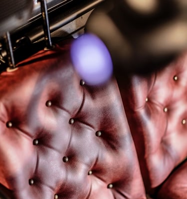 A vintage red tufted leather upholstery with decorative brass studs and soft bokeh lighting.