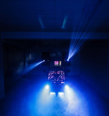 Professional DJ setup with blue stage lights and fog machine effects in a dark event venue.