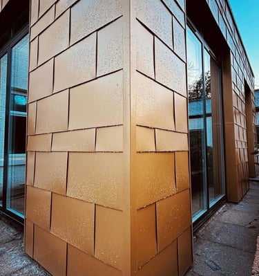 Modern building exterior featuring bronze architectural metal rainscreen cladding panels.