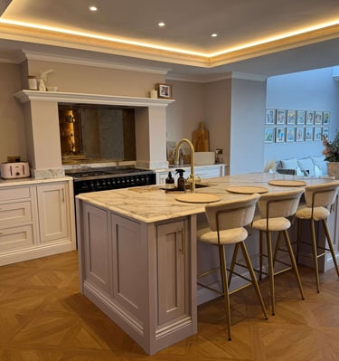 Luxury kitchen with marble island, gold hardware, and bar stools under warm cove lighting.