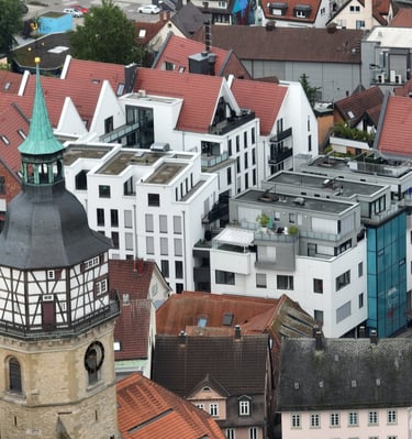 Aerial view of a German old town featuring a historic church tower and modern white apartments with red tile roofs.