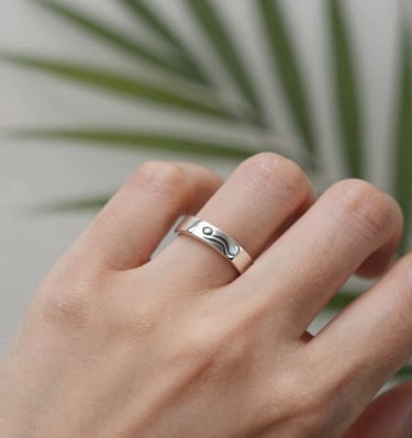 Close-up of a handcrafted silver ring resting on a smooth jade stone.