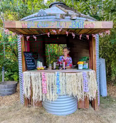 A woman serves drinks at a tropical-themed tiki bar built inside a repurposed metal grain silo.