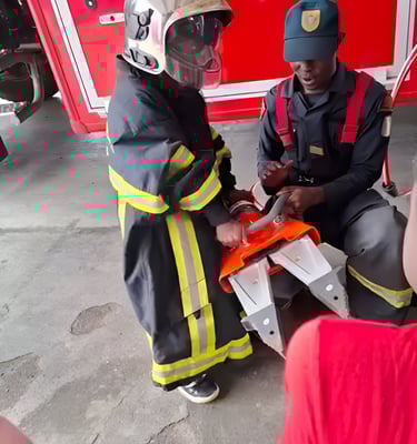 A professional firefighter helps a child from the creative workshop put on a firefighter uniform to 