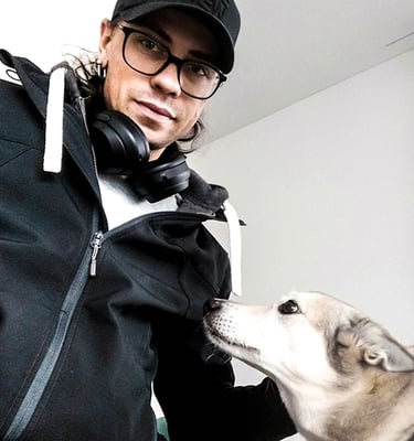 lächelnder Mann mit Brille und schwarzer Baseballkappe mit grauem Hund