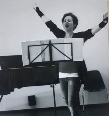 eine junge Frau - Sina Weidlich - singt, die Arme hoch erhoben, im Hintergrund ein Flügel