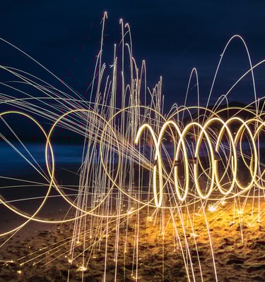 Spiraling fire lights at night on a sandy beach