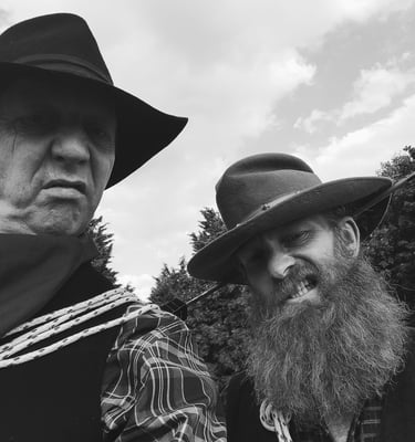 Two men wearing vintage cowboy hats and western attire in a black and white portrait.