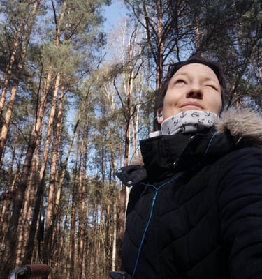Tonia in a black jacket and a bicycle, in the woods