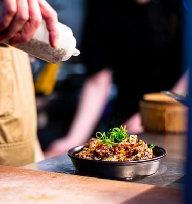 pouring sauce over an ovendish made by a chef