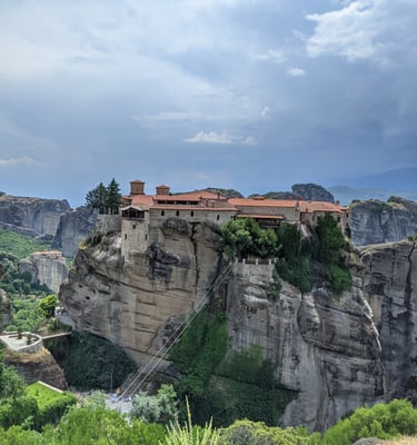 A red roofed monastery in Meteora, Greece perched precariously on a rock spire. 