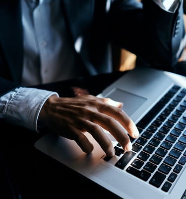 a man in a suit and tie is typing on a laptop