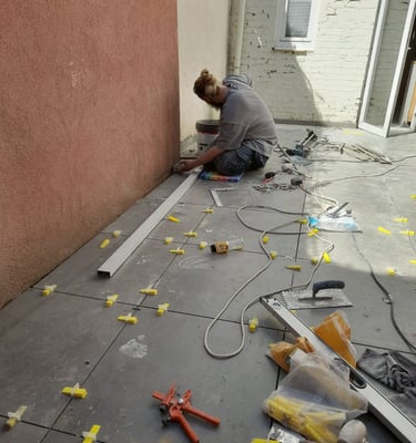 Pose de carrelage extérieur grand format avec croisillons de nivellement dans une cour intérieure