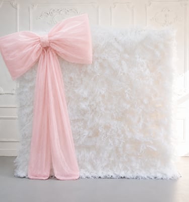 Elegant white tulle backdrop with a large decorative pink bow for events.