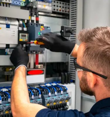 a man in a blue shirt and gloves is working on a machine