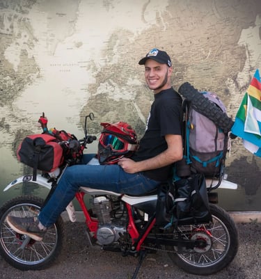 a man sitting on a motorcycle with a backpack on it