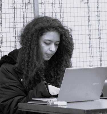 a woman with curly long hair sitting at a table with a laptop
