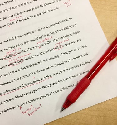typed page with corrections in red and a red pen