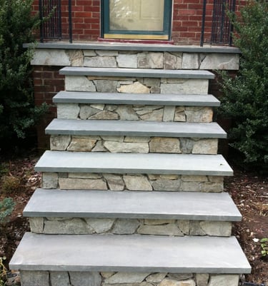 Custom bluestone front steps with natural fieldstone risers leading to a brick house entrance.
