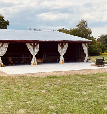 a barn with a covered patio decorated for fall with pumpkins