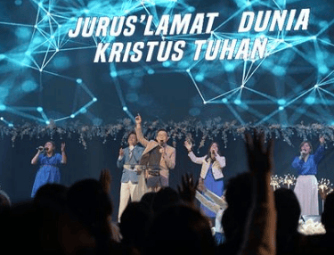 a group of people standing on a stage with hands up in the air