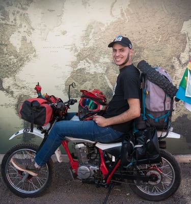 a man sitting on a motorcycle with a backpack on it