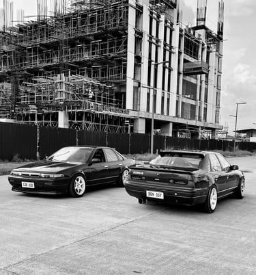 Nissan A31 cars parked on the road with scaffolding in the background