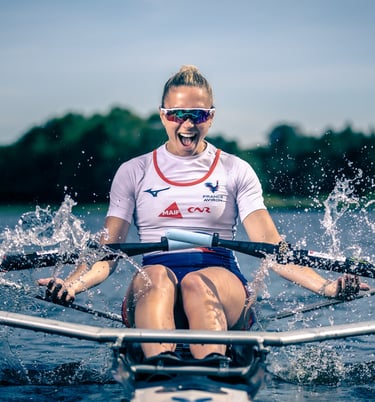 Sport portrait of an athlete rowing a single scull on the water, facing forward.