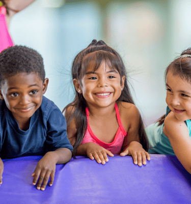 three young children in colorful gym attire are smiling and posing for a picture