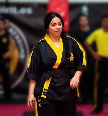 a woman in a black and yellow uniform is standing in a karate pose