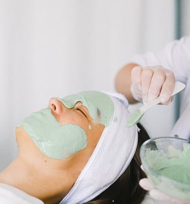 therapist apply clay mask with brash on face 