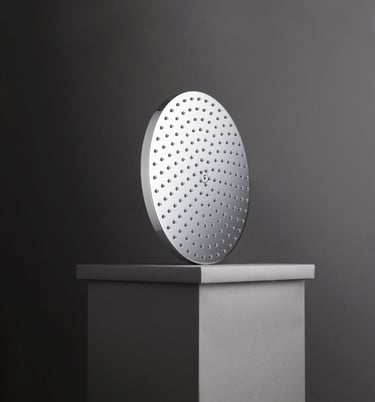chrome rain shower head balanced on grey plinth