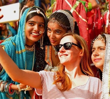 a group of women in colorful saris taking a selfie