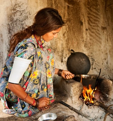 a woman in a floral print dress is cooking in a pot