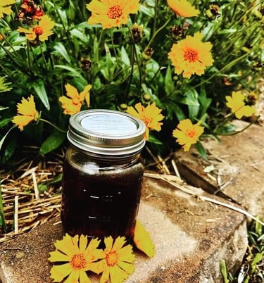 jar of honey on block sitting in yellow flowers