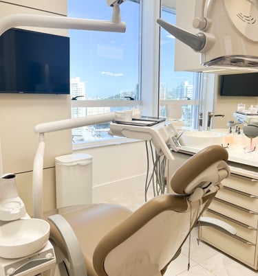 a dental room with a dental chair, a TV, some equipments and a window with a view