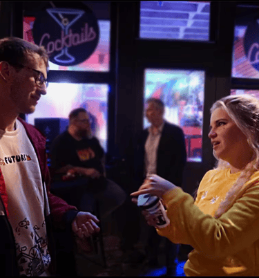 a man and woman standing in front of a bar