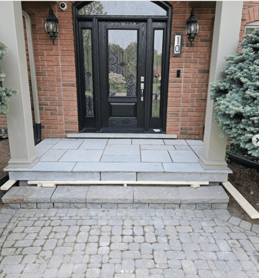 a front door with a black door and a brick wall