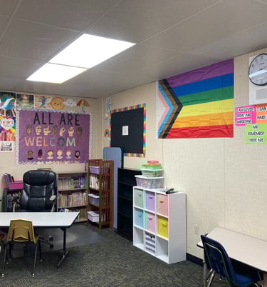 a classroom with a desk and chairs and a clock