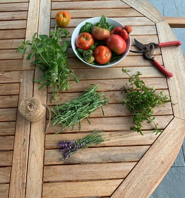 Heirloom tomatoes, fresh herbs, gardening tools and twine on an outdoor wood table
