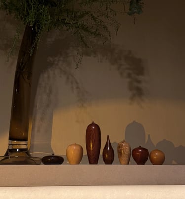 Hand-turned wooden bud vases in various grains and shapes displayed on a shelf with moody lighting.