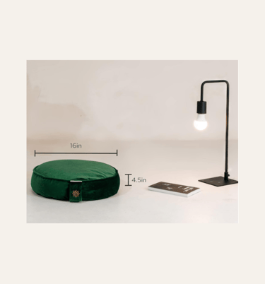 a picture of an emerald green round meditation cushion on a floor with a lamp beside it