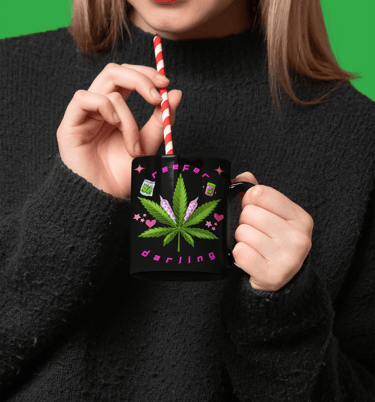 a woman holding a straw and drinking from a mug with cannabis imagery